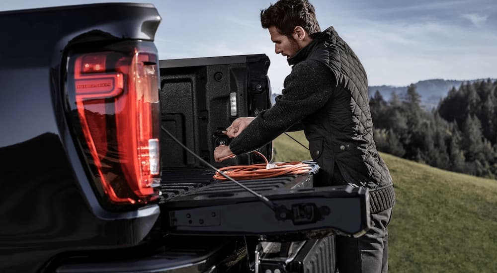 A man is working on the tailgate of a 2023 GMC Sierra 2500 HD Denali HD.