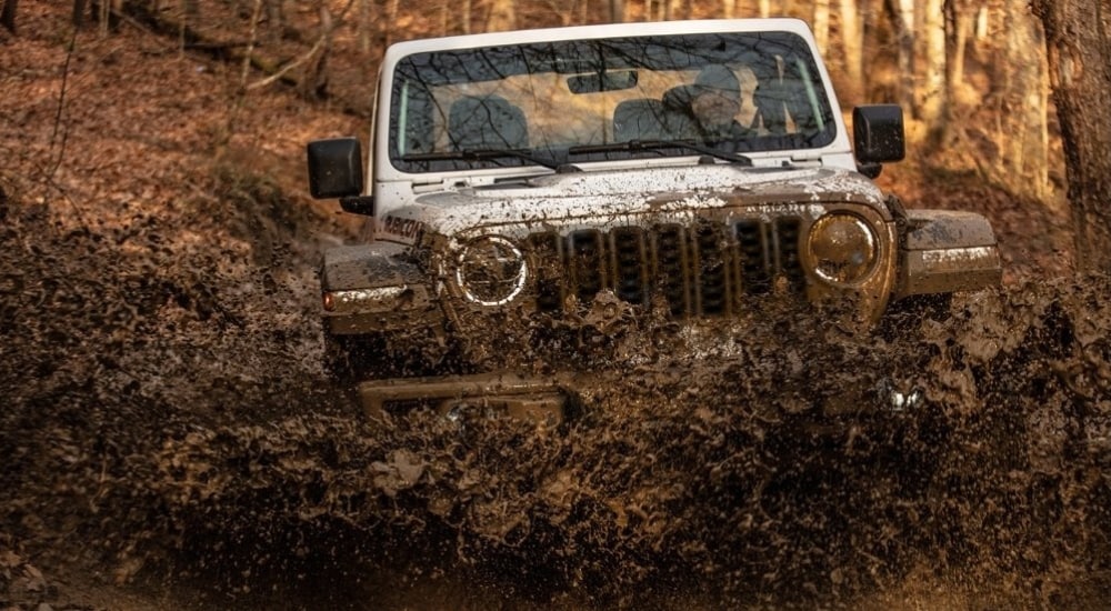 Silver 2024 Jeep Wrangler Rubicon kicking up mud