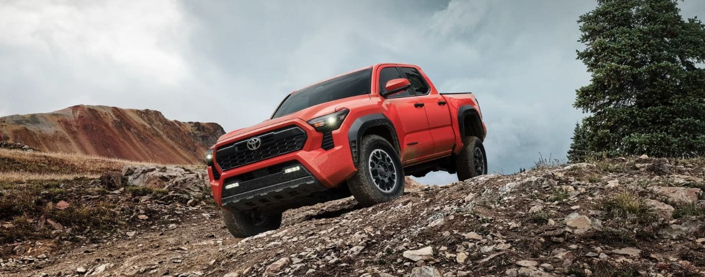 A red 2024 Toyota Tacoma TRD Off-Road off-roading down a dirt hill.