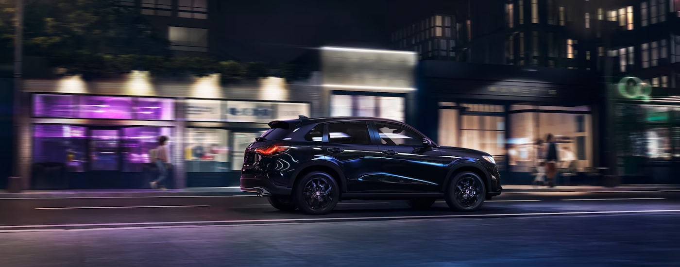 Black 2025 Honda HR-V driving on a city street at night