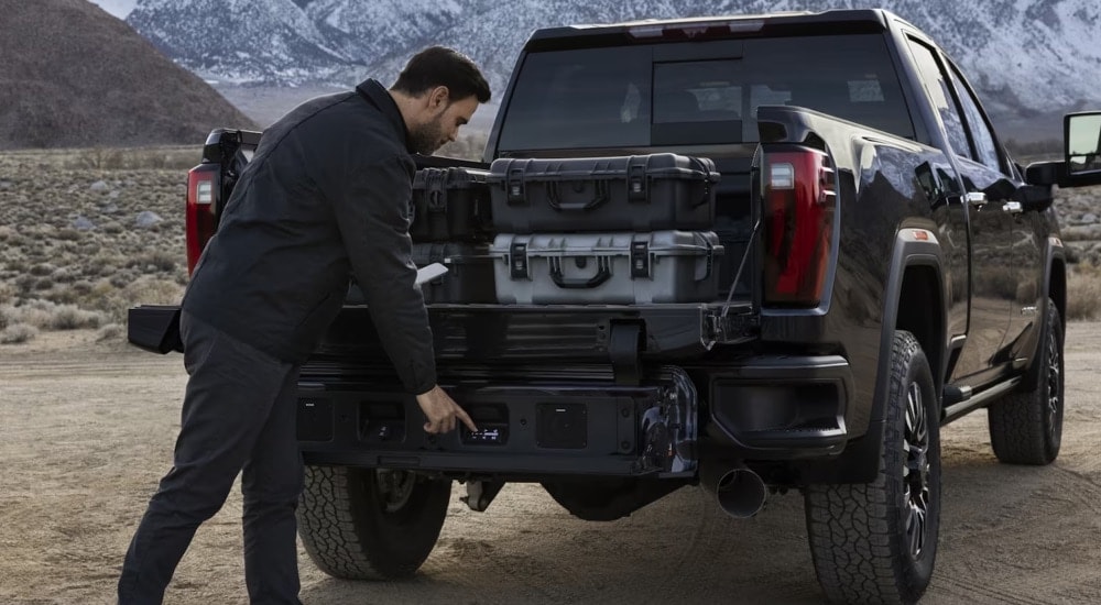 A man using the MultiPro tailgate on a black 2024 GMC Sierra HD Denali.