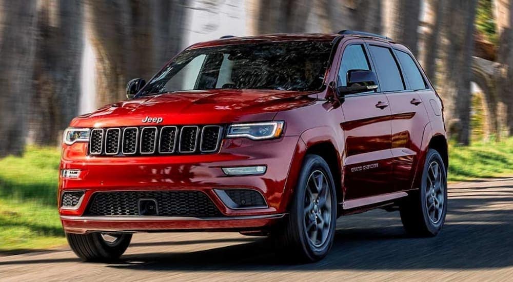 Used%20Vehicles%20for%20Sale%20Near%20Me%20-%202020%20Jeep%20Grand%20Cherokee%20-%20Red%20(1).jpg A red 2020 Jeep Grand Cherokee is shown driving near a forest.