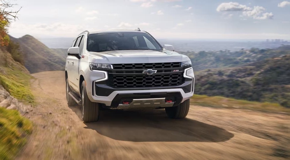 A white 2023 Chevy Tahoe Z71 is shown driving off-road after visiting a used car dealership near Charleston.