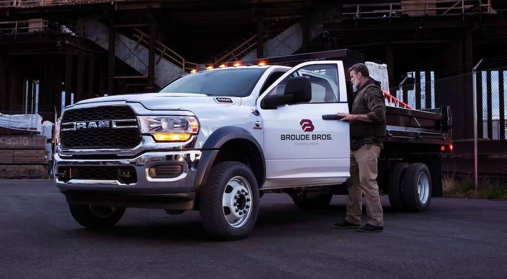 A white 2024 Ram 5500 Chassis Cab is shown parked in a lumber yard.