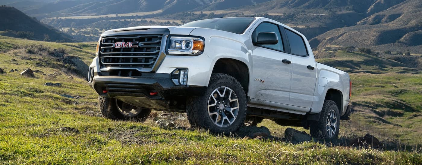 A white 2021 GMC Canyon AT4 parked on a grassy hill after viewing used cars for sale in Charlotte.
