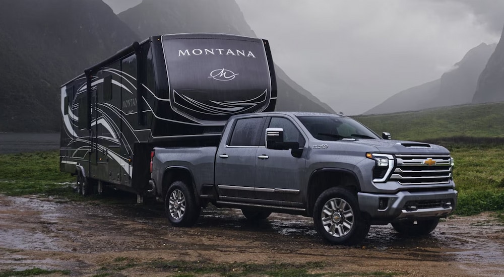 A grey 2024 Chevy Silverado 2500 High Country towing an RV through the mud.
