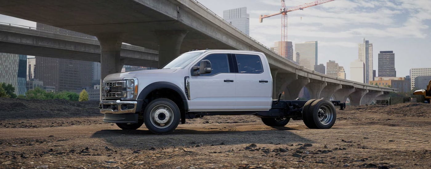 A white 2024 Ford F-550 Chassis Cab parked at a highway construction site.