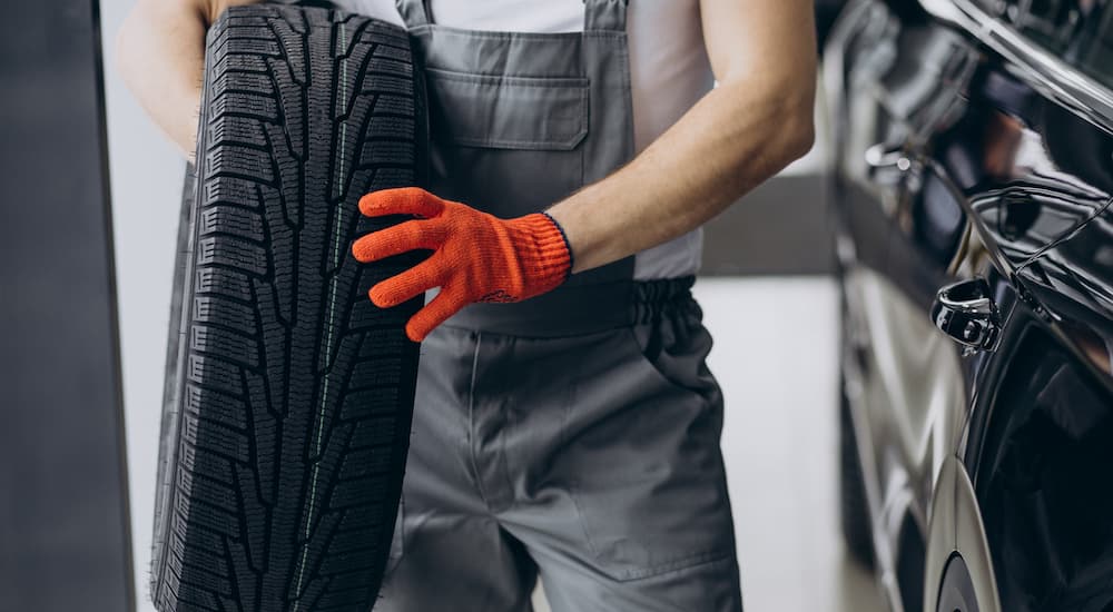 A mechanic is holding a tire at a service center in Raleigh.
