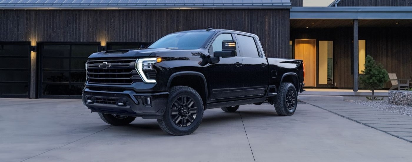 A black 2024 Chevy Silverado 2500 HD High Country angled left and parked outside a building.