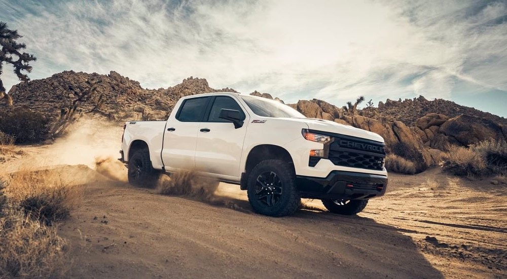 A white 2023 Chevy Silverado 1500 Z71 Trail Boss off-roading in sand