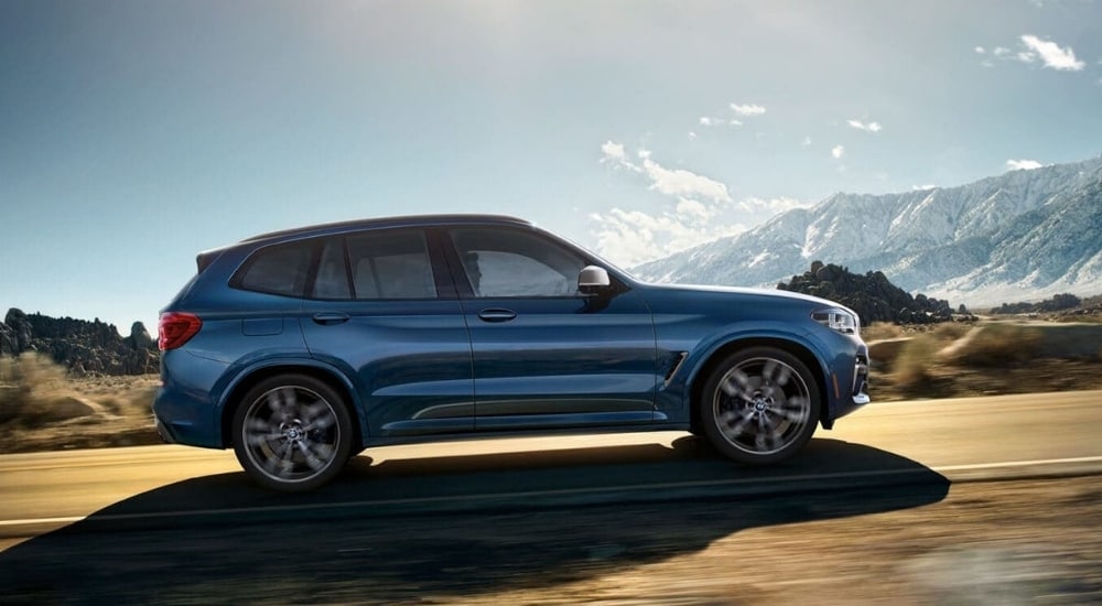 Blue 2018 BMW X3 driving to see cars for sale