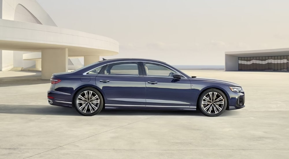 A blue 2025 Audi A8 S-Line is shown from the side.