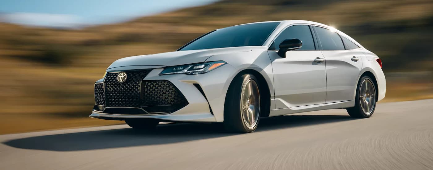 A white 2022 Toyota Avalon Touring is shown driving after leaving a used car dealership near Wilmington.