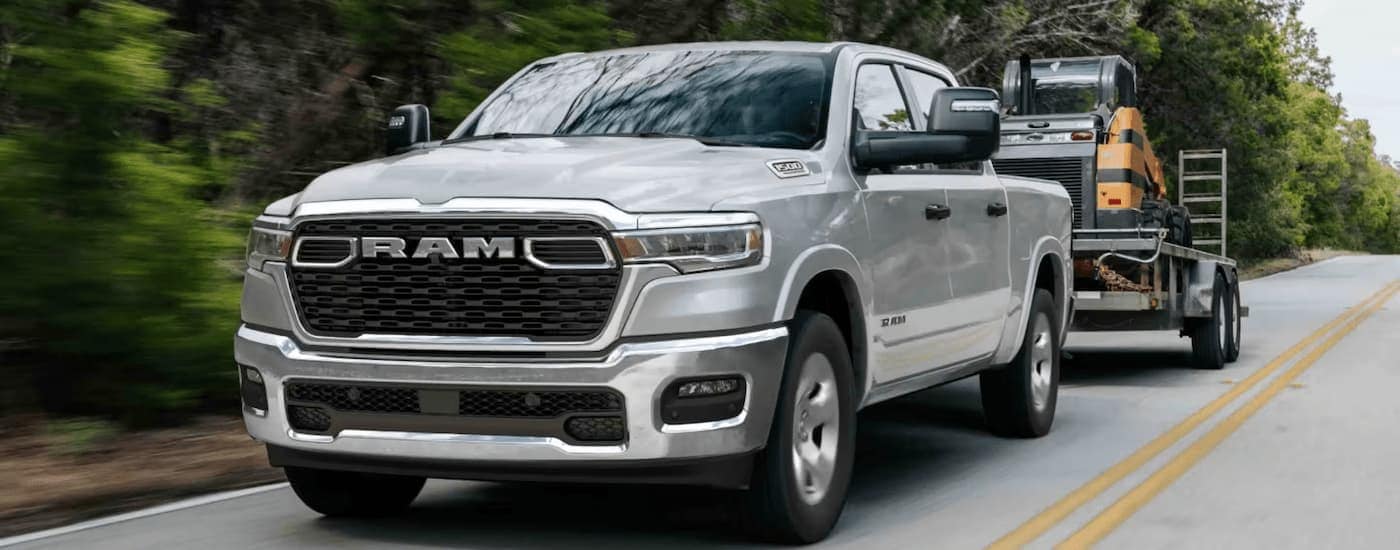 Silver 2025 Ram 1500 Big Horn towing heavy machinery