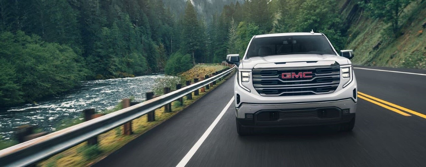 A front angle view of a white 2024 GMC Sierra 1500 SLE driving from a truck dealership near Wilmington.