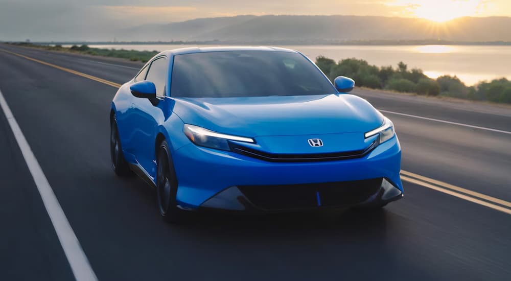 A blue 2026 Honda Prelude driving down a highway