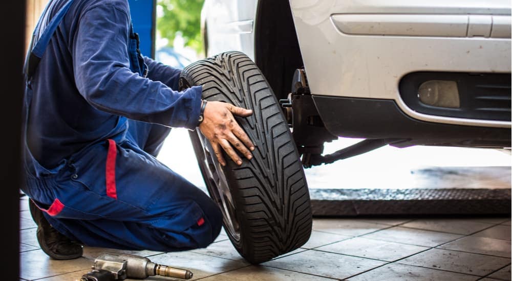 A mechanic is rotating tires on a vehicle that recently had service done.