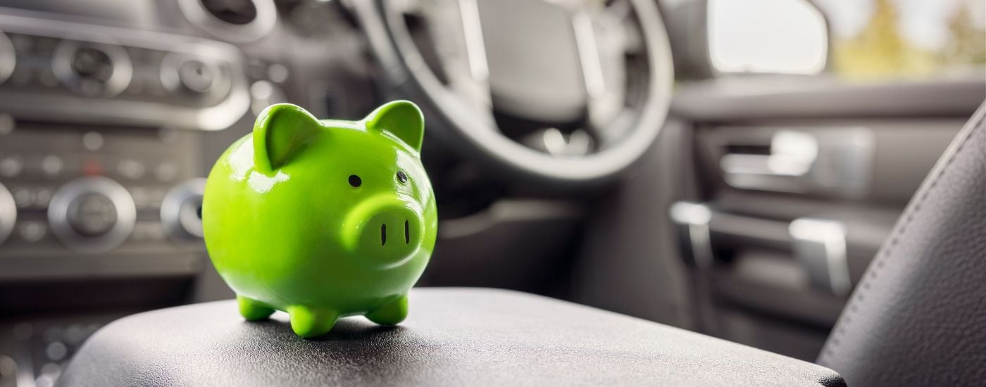 A green piggybank is shown in a vehicle.