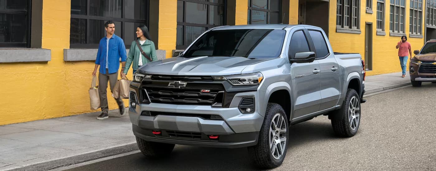 A silver 2024 Chevy Colorado Z71 is parked on the side of a city street.