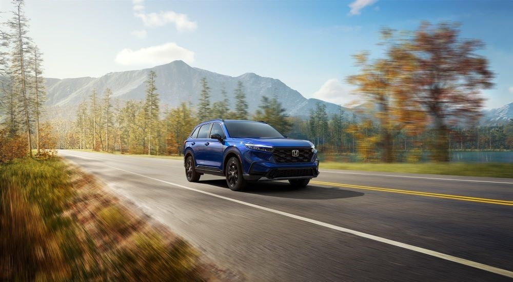 A blue 2024 Honda CR-V driving from a SUV dealership near Atlanta.