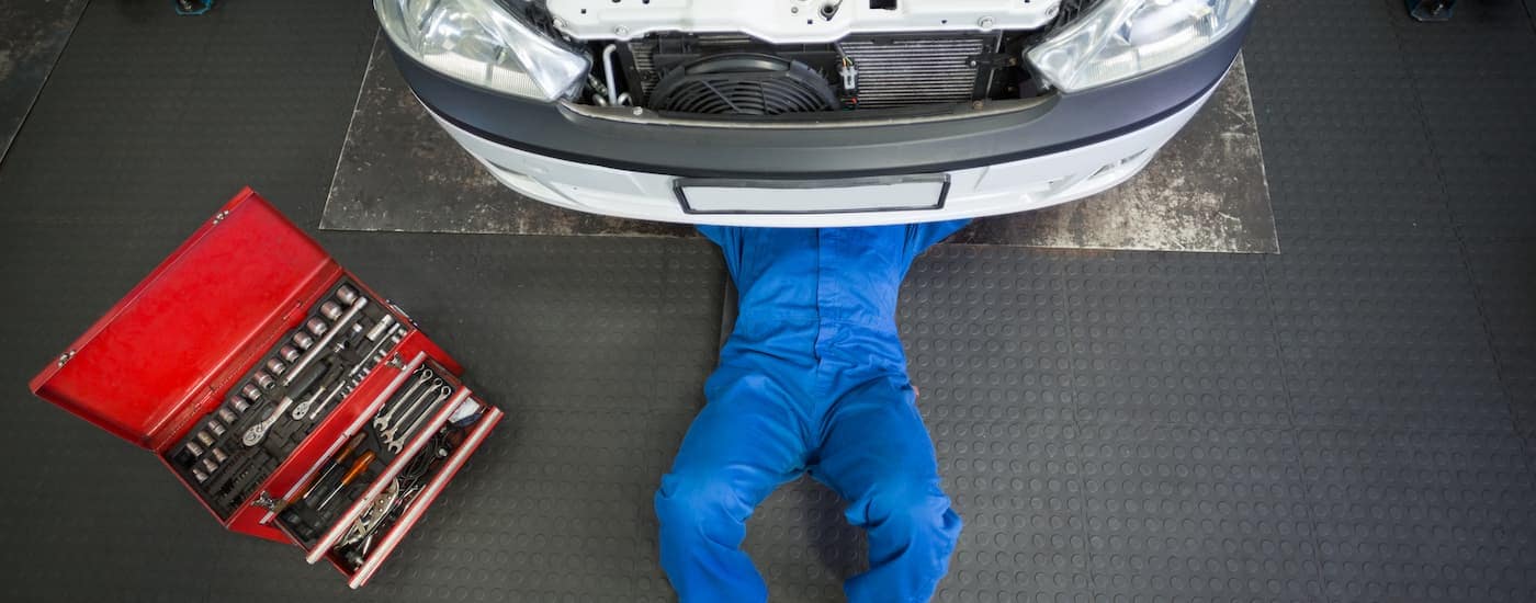 A mechanic is working underneath a white vehicle at a service center in Wilmington.