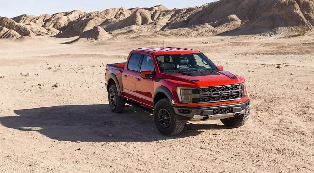 A red 2023 Ford F-150 Raptor is shown parked off-road.