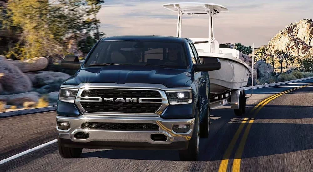 A blue Ram 1500 is shown towing a boat after viewing work trucks for sale in Atlanta.