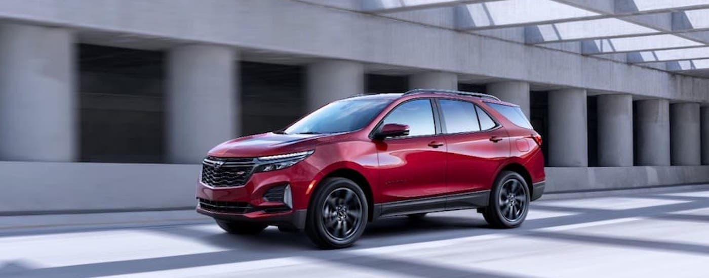 A red 2022 Chevy Equinox RS is shown from the front at an angle on a highway after leaving a car dealership in Wilmington, NC.