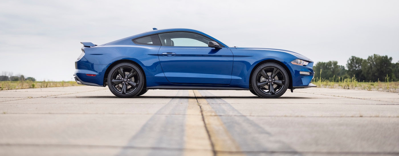 A blue 2023 Ford Mustang Ecoboost is shown from the side on a runway.