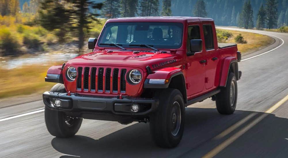 A red 2021 Jeep Gladiator Rubicon is shown driving on a highway after visiting a used car dealership near Charlotte.