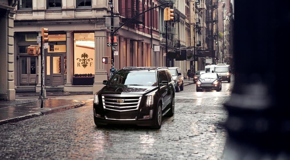 A black 2020 Cadillac Escalade is shown driving in a city after visiting a used car dealership.