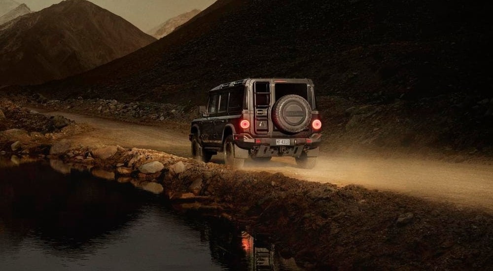 Rear of a black 2025 INEOS Grenadier driving off-road.