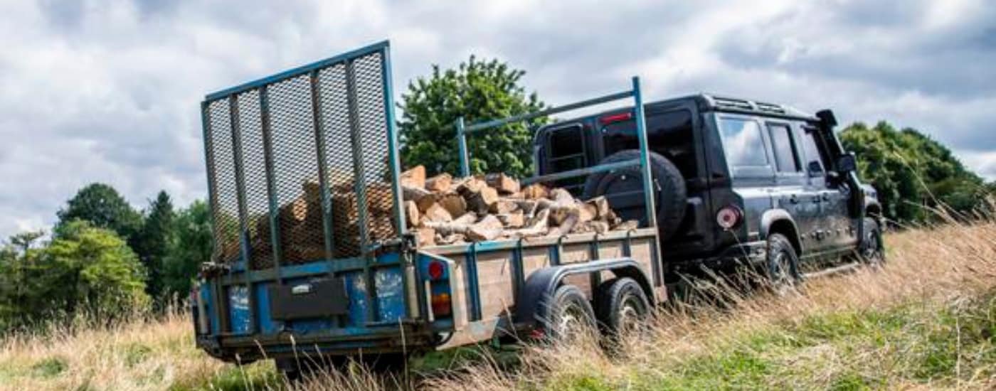 Black 2025 INEOS Grenadier Trailmaster towing wood