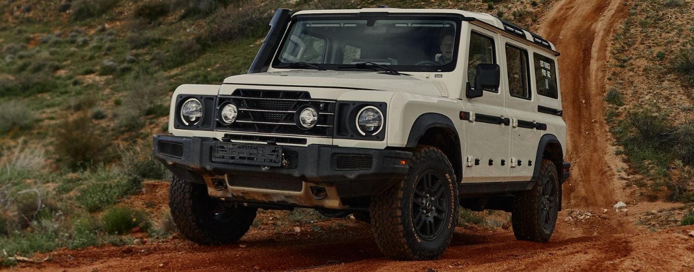 White 2025 INEOS Grenadier driving on a remote dirt road