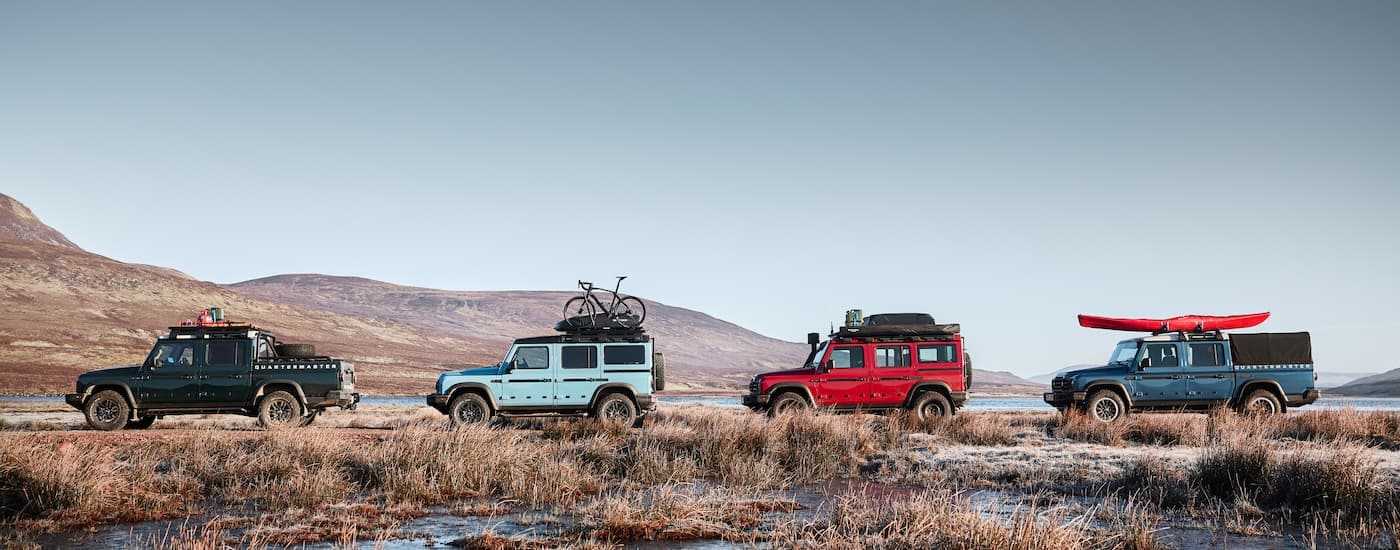 Four 2025 INEOS Grenadier vehicles off-roading through a grassy area