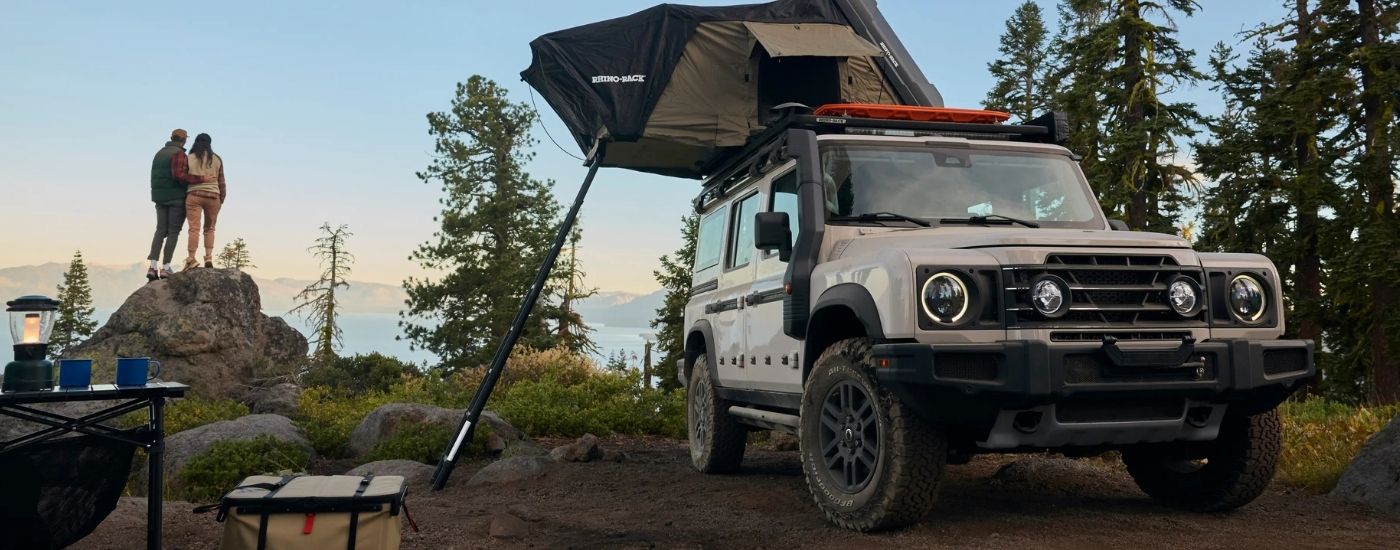 Grey 2025 INEOS Grenadier parked at a remote campsite with a rooftop tent
