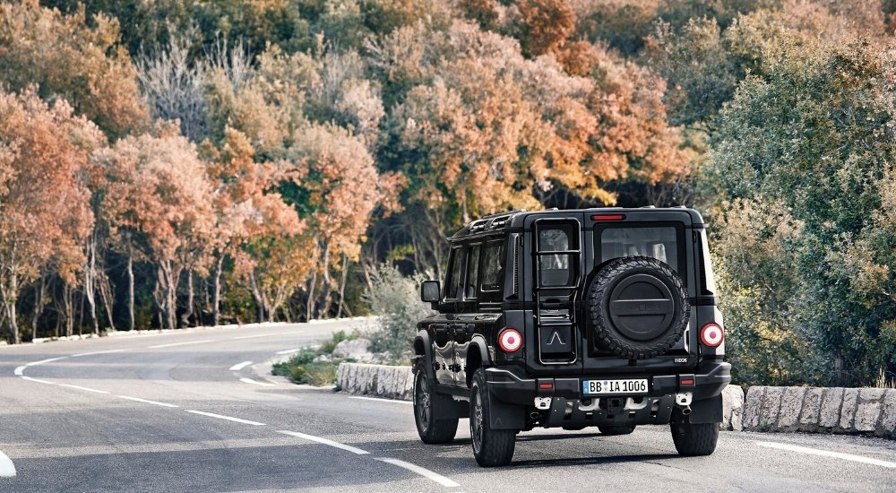 A black 2025 INEOS Grenadier Station Wagon is shown rounding a corner.