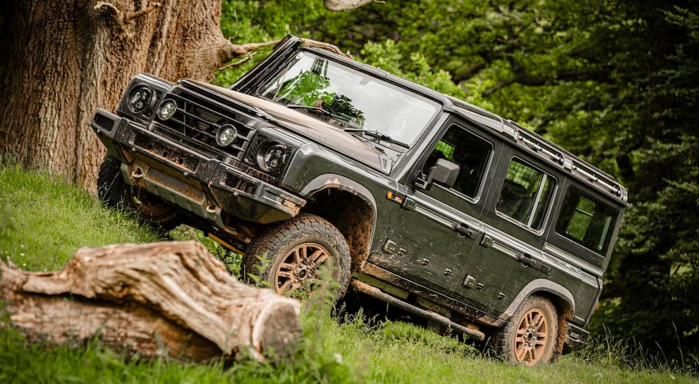 A grey INEOS Grenadier off-roading through grass.