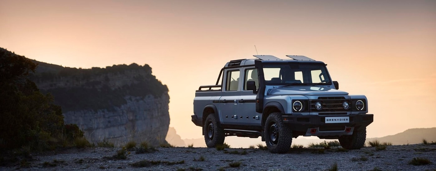 A silver 2025 INEOS Grenadier Quartermaster is shown at dusk after visiting an INEOS dealer.