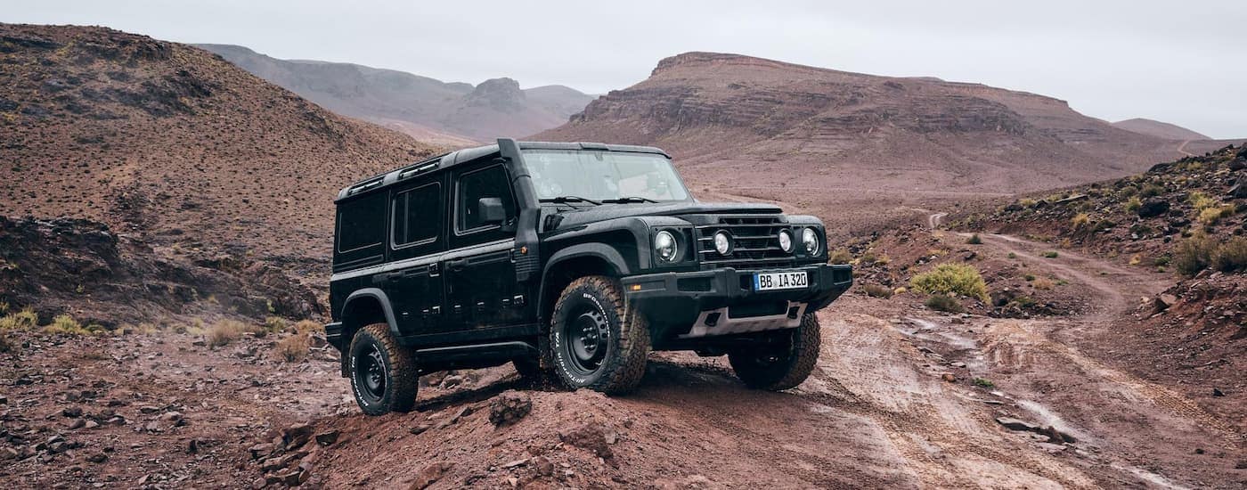 Black Ineos Grenadier off-roading on a dusty trail.