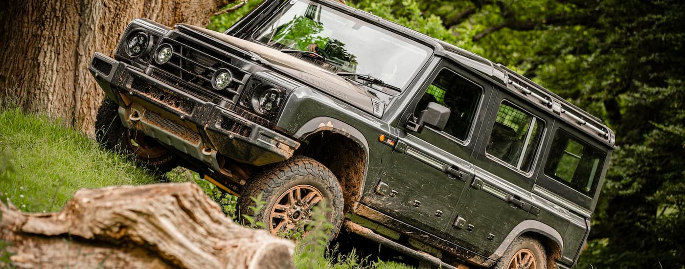 Green 2025 INEOS Grenadier driving off-road up a hill.