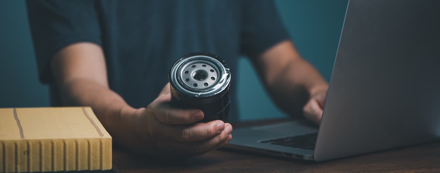 A car mechanic is holding an oil filter.