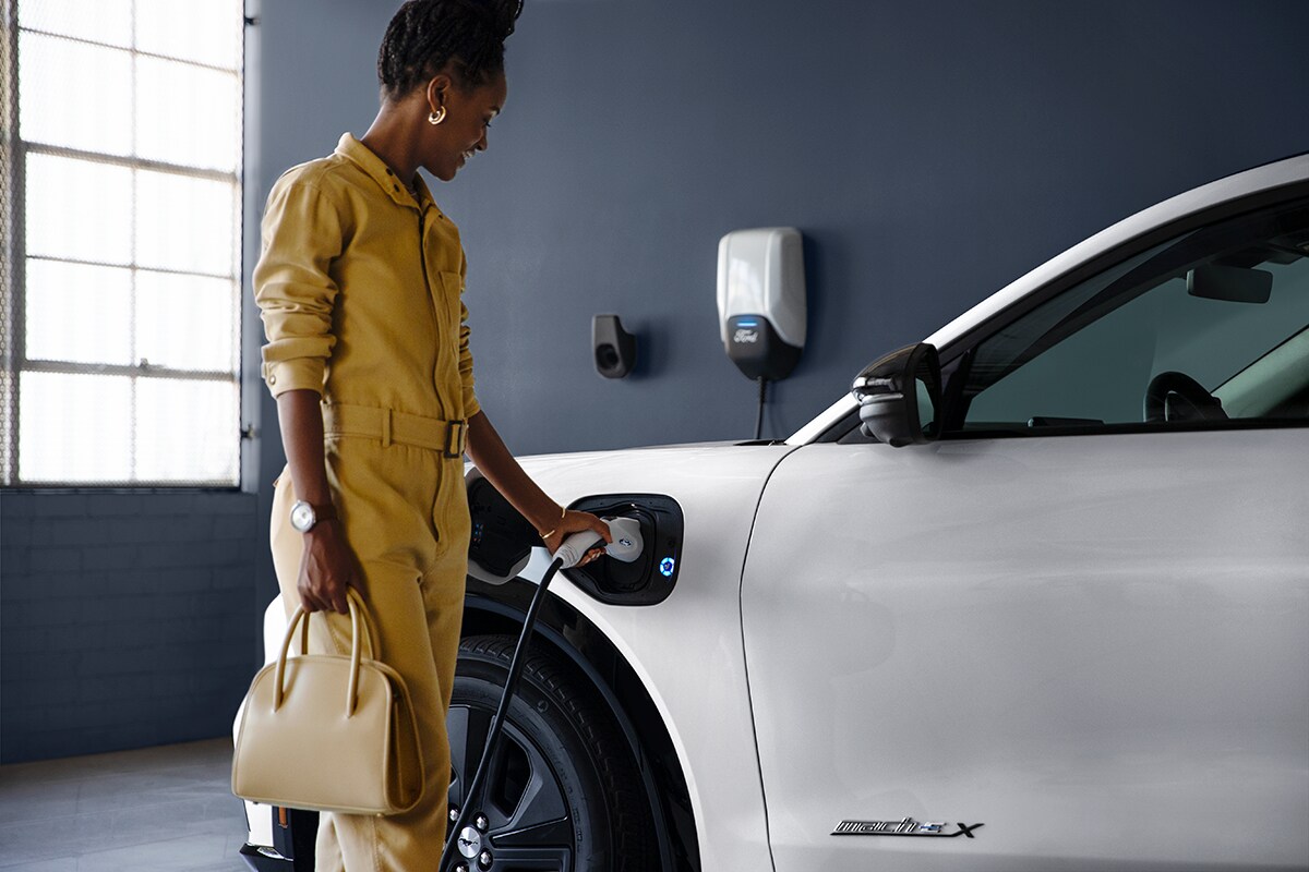 Woman charging her electric vehicle with an at home charger