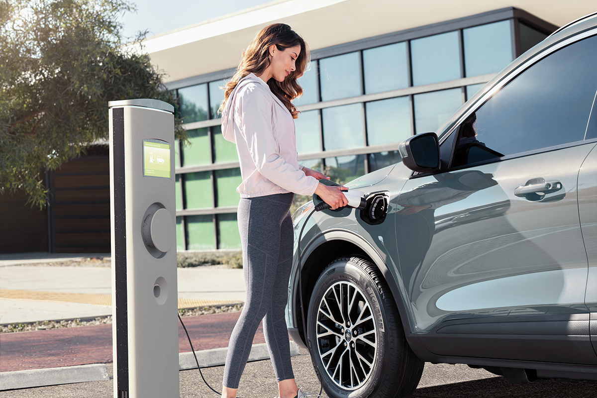 Woman charging her electric vehicle outside