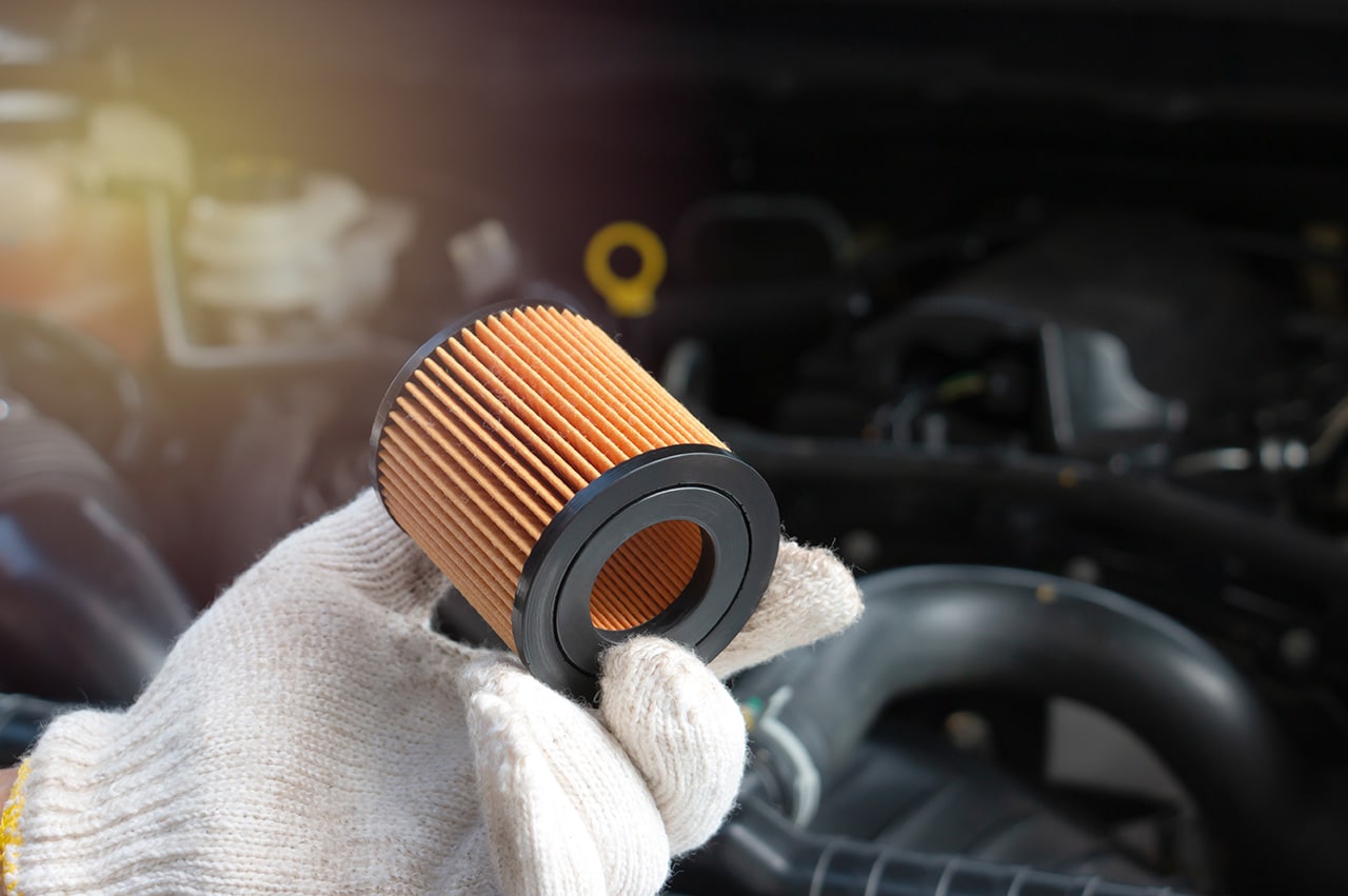 gloved hand holding filter in front of car