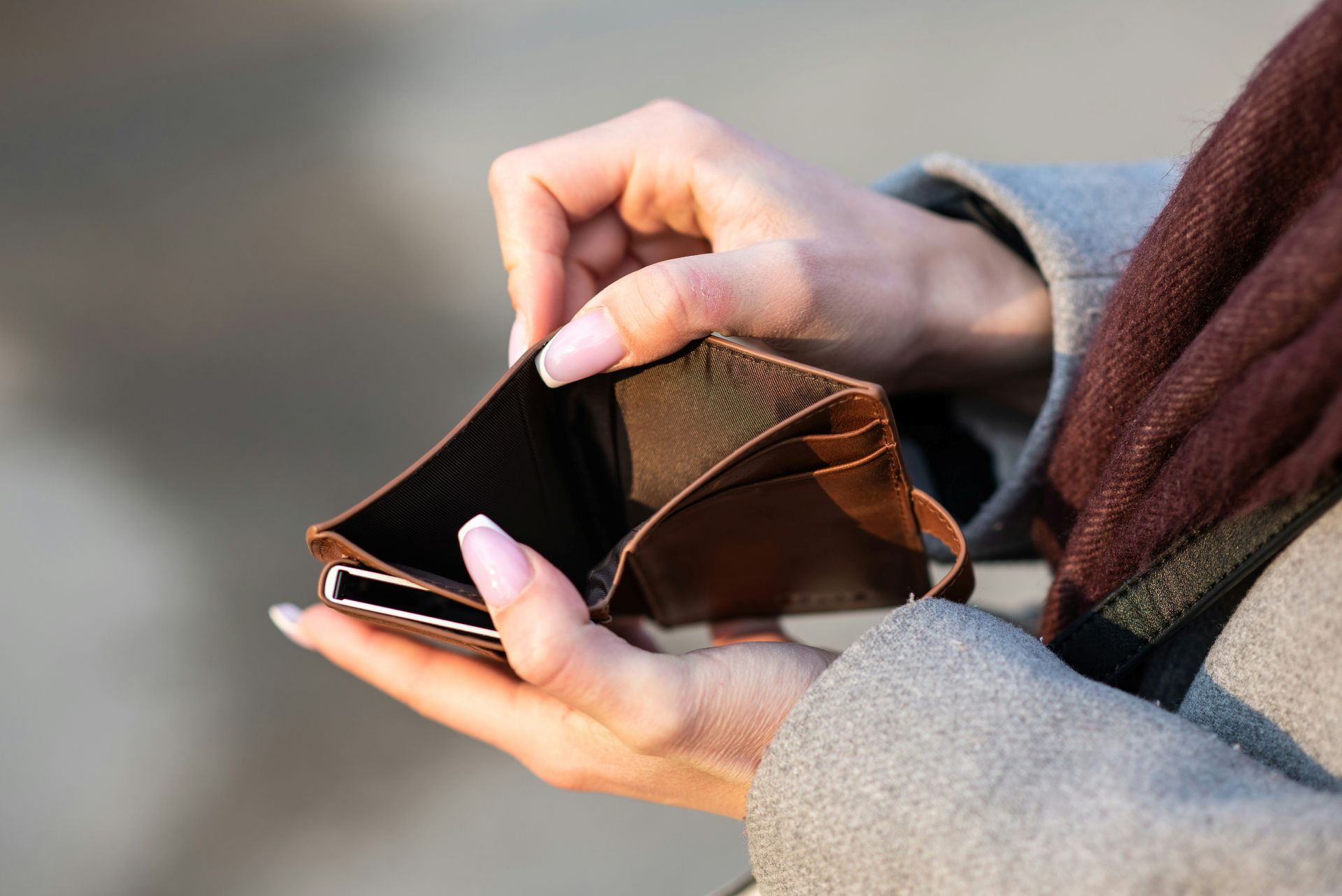 woman with French manicure opening an empty leather wallet