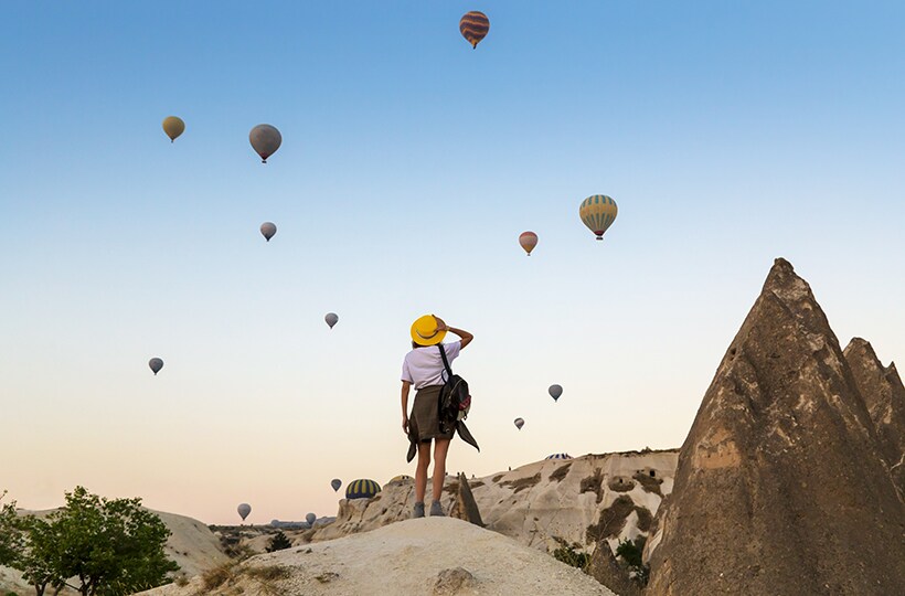 Woman looking at hot air balloons in the distance