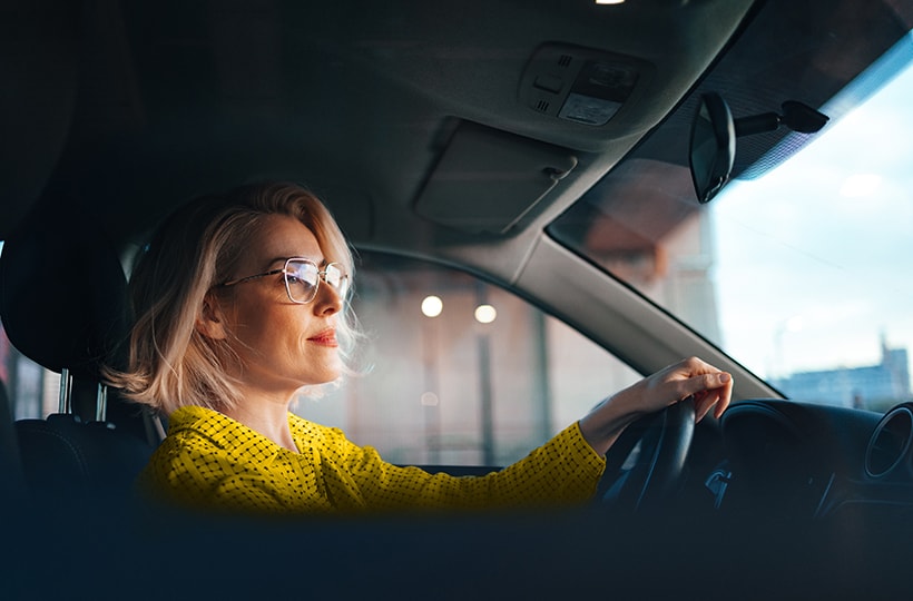 A woman driving a car while looking in the rearview mirror