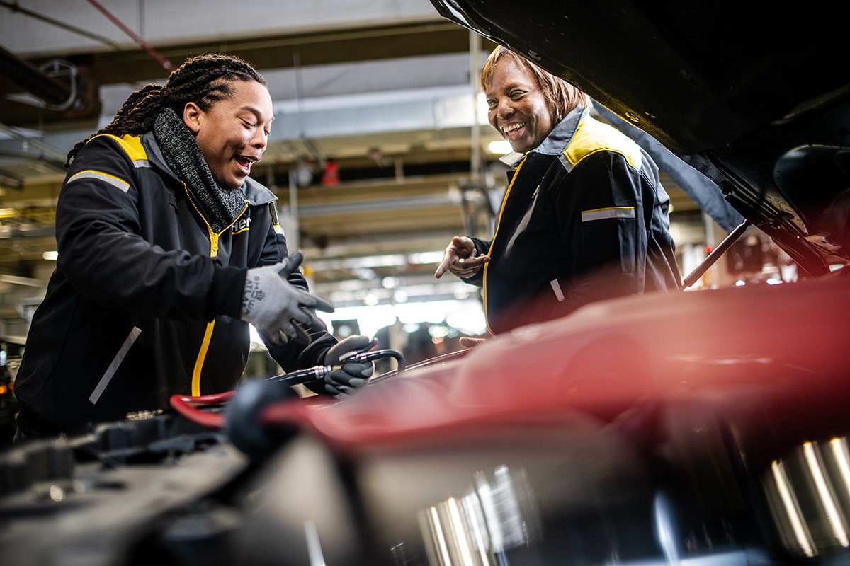 Two female mechanics working on a car in the service drive