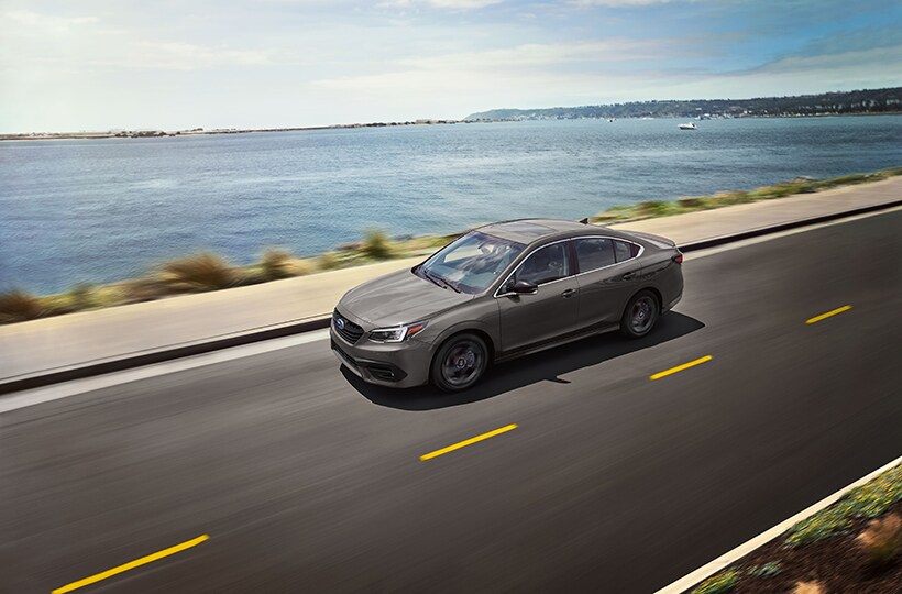 A Subaru Legacy driving along a seaside road